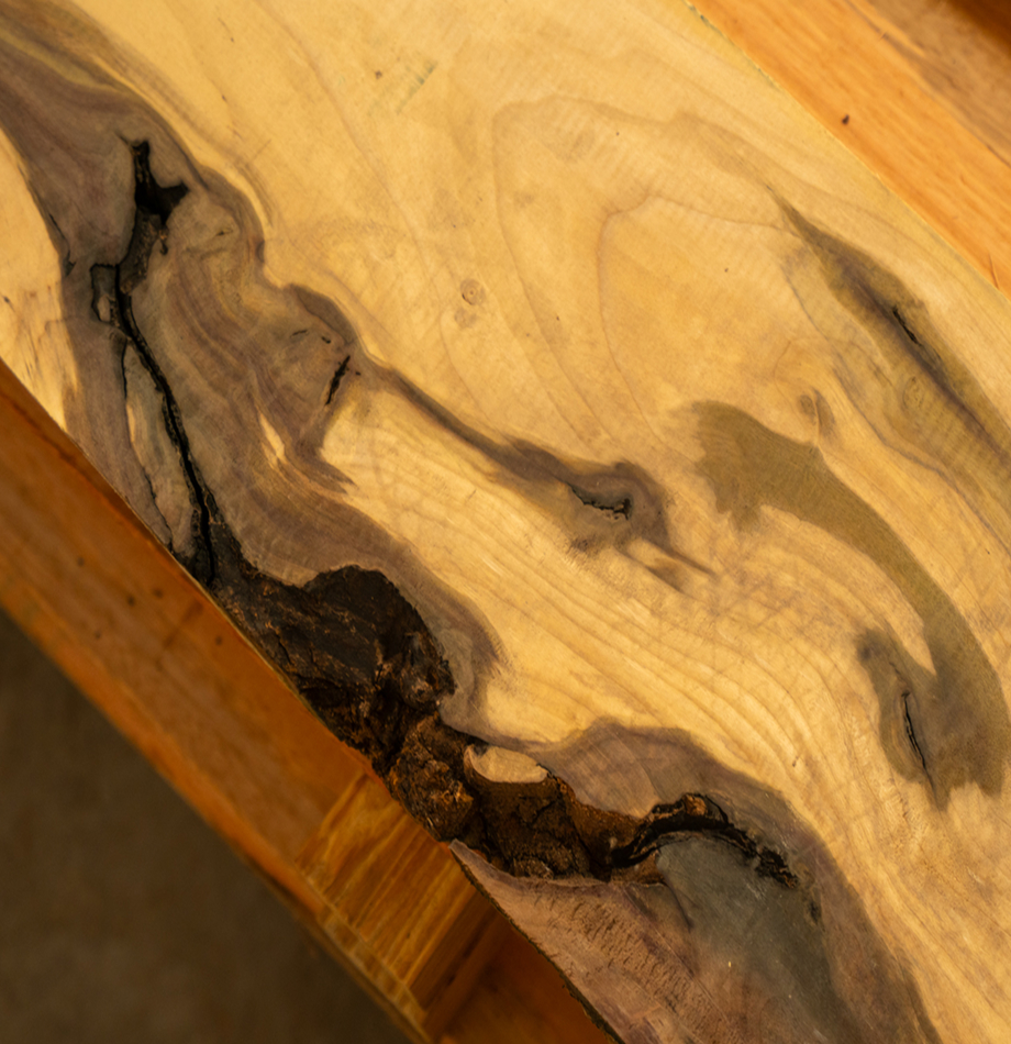Hardwood lumber slab with unique dark mineral streaking and a natural live edge.