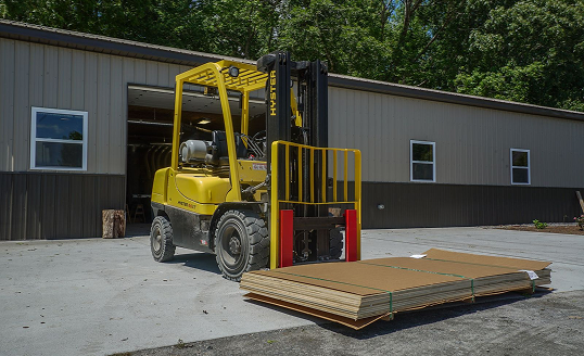 Yellow forklift with lumber outside Cygnus Lumber facility. Contact Cygnus Lumber for orders.