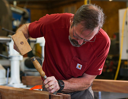 Dedicated craftsman shaping lumber with mallet and chisel. Contact Cygnus Lumber for details.