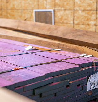 Stacked purple-treated lumber planks. Contact Cygnus Lumber for product inquiries.