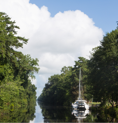 Chesapeake: White sailboat moored in a narrow tree-lined canal.