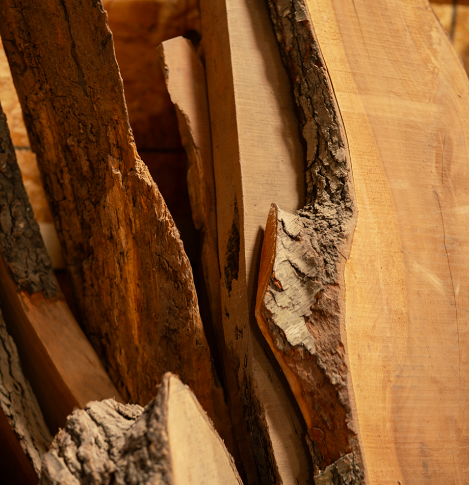 Raw live-edge wood slabs showing natural bark texture.