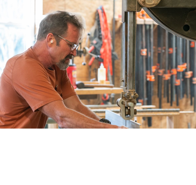 Woodworker wearing safety glasses operating a band saw in a workshop.
