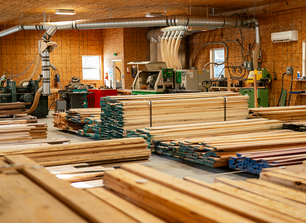 Stacks of lumber and woodworking machinery inside a workshop.