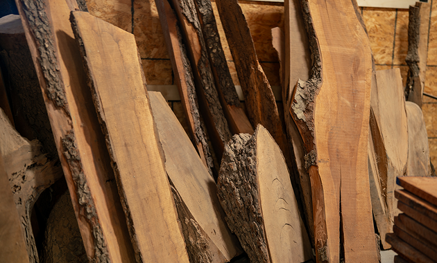 Live-edge wood slabs with bark leaning in a workshop.