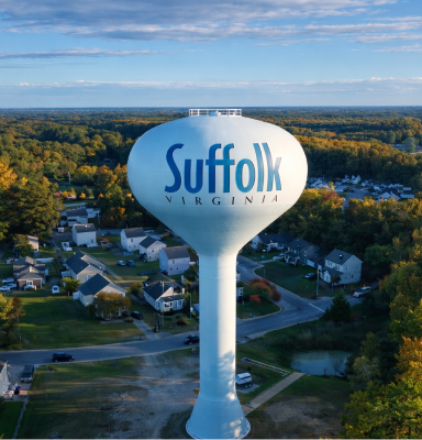 White water tower reading Suffolk Virginia over a residential area.