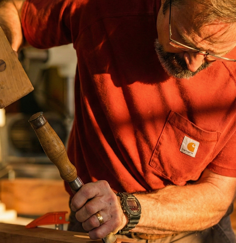 Woodworker using a mallet and chisel on a wooden project.