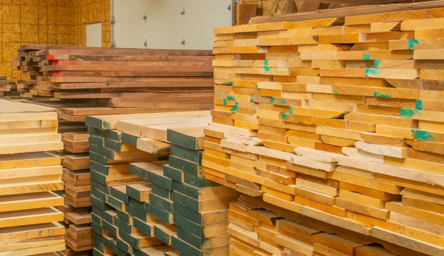 Neat, large stacks of processed timber boards inside a lumber storage facility.