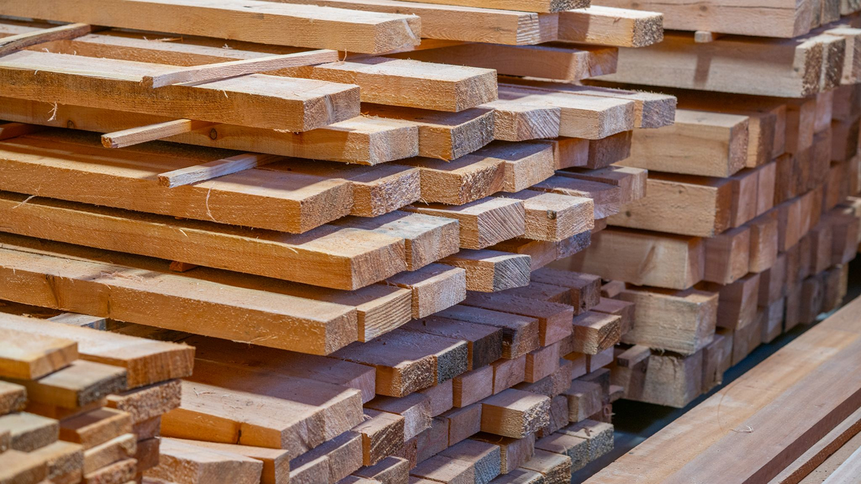 Close-up of neatly stacked raw wooden boards and timber planks in a workshop.